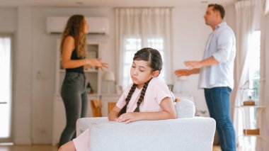 Sinirli ve mutsuz genç bir kız oturma odasında ebeveyninin tartışması yüzünden gerginliğin ortasında kanepede oturuyor. Sağlıksız ev hayatı ve travmatik çocukluk depresyon senkronlarına dönüşür.