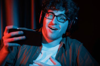 Stresli genç oyun flaması takımı akıllı telefondan Esport 'la oynuyor. Daha sert oyun seviyesinde, neon ışıklı odada kazanmanın utancı ve şaşkınlığı ile mücadele ediyorlar. Strateji planı uyguluyorum. Toplayıcı.