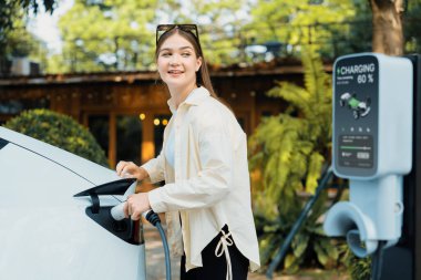Genç kadın ve sürdürülebilir kentsel yol, bahar bahçesi, yeşil şehir sürdürülebilirliği ve çevre dostu EV arabadaki açık kafede çalışan EV elektrikli araba. Yararlı
