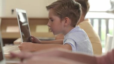Bilgisayar üzerinde çalışan beyaz çocuğun yan görüntüsü. Mühendislik ödevi sırasında. Çekici çocuklar bilgisayar yazılımı kullanarak yapay zeka ya da programlama sistemini öğreniyor ya da öğreniyor. Pedagoji.