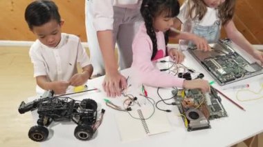 Kafkas öğretmeninin en iyi görüşü öğrencilere dijital elektrikli aletleri öğretmek ve açıklamak. Kız elektronik aletleri öğreniyor ve ana kartı tamir etmek için çipleri ve kabloları yerleştiriyor. Etkinlik.