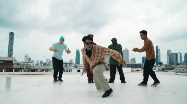 Profesyonel break dans takımı çatıda çok kültürlü arkadaşlar varken break dans alıştırması yapıyor. Genç modern dans grubu hip hop hareketi yapıyor. Tarz, moda, aksiyon. Açık hava sporu 2024 hiphop..