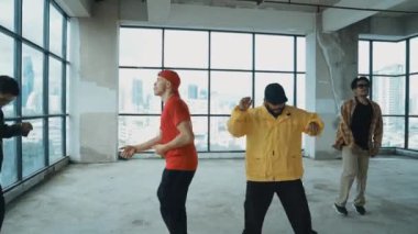 Çok kültürlü hipster grubu kameraya bakarken gökyüzü avcısıyla ya da şehir manzaralı bir binada break dans yapıyorlar. Sokak dansçısı ekibi dansçı performansına bakıyor. Açık hava sporu 2024 hiphop..