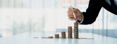 Büyüyen madeni para yığını iş yatırımını ve ekonomik büyümeyi simgeliyor. Finansal hedefe ulaşmak ve maksimum kâr sağlamak için finansal planlama yapan iş adamları. Kurnaz.