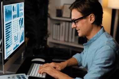 Akıllı iş adamı iş paragrafı dinamik pazarlama analizi planını analiz ediyor. Kağıt kağıtları ve bilgisayar monitörü raporlarını gece evdeki belge verileriyle karşılaştırmak için hazırlıyor. Bireysel.