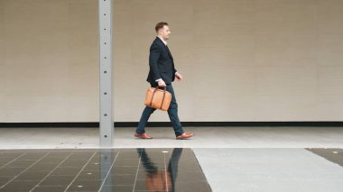 İş adamlarının bavul tutarken ve şehir merkezindeki iş yerine yürürken yan görüntüsü. Profesyonel proje yöneticisi dışarıda resmi takım elbise giyerken toplantıya gidiyor. Urbane.