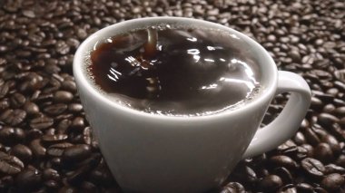 Kahve çekirdeğini yaklaştır ve kahve çekirdeği yığınıyla birlikte sıcak espresso 'ya bırak. Makro taze kavrulmuş fasulye aromatik dumanla bardağa düşüyor. Ağır çekim. Organik kahve tohumu kavramı. Geliştirilebilir.