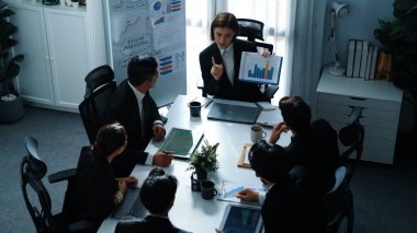 Akıllı iş kadınlarının en üst görüşü çeşitli iş adamlarına satış tablosunun arttığını gösterirken, bir grup farklı iş adamı da masada belgelerle hisse yatırım verilerini dinleyip analiz ediyor. Müdürlük.