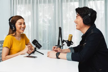 Gülümseyen radyo etkili sunucusu kulaklık takıyor kadın konuşmacı ile röportaj yapıyor sosyal medya internet sitesinden dinleyicilere bilgi paylaşıyor stüdyo kaydında sabah canlı yayın kanalı. İnfobahn.