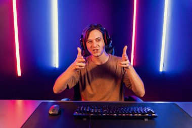 Kazanmak için çevrimiçi oyun oynayan akıllı flama makinesinin sunucu kanalı, neon ışıklı odada seçilen takım yarışması için izleyicilerle birlikte canlı yayında canlı yayında kulaklık takıyor. Bireysel.