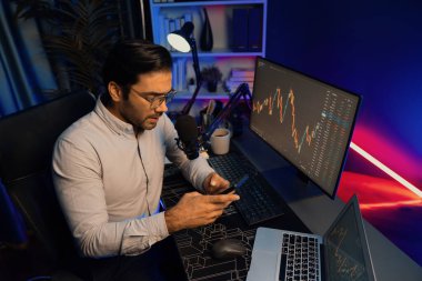 Akıllı tüccar akıllı iş adamı akıllı telefonu kullanarak modern evde kâr amaçlı finans teknolojisi ile neon ışık ofisindeki bilgisayarda dinamik borsa yatırımlarını araştırır ve analiz eder. Tahmin et..