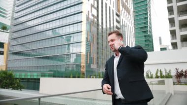 Zeki beyaz iş adamı, çatıda dururken iş arkadaşını mali strateji planlaması için arıyor. Proje yöneticisi pazarlama ekibiyle iletişim kurmak için cep telefonunu kullanıyor. Yaşam tarzı. Urbane.
