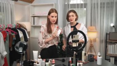 İki kadın nüfuzlu partner sosyal medya veya blog için canlı yayın yapan video klip inceleme derisi çekiyorlar. Kozmetik stüdyosu ışıklandırması olan genç bir kız pazarlama oturumu çevrimiçi yayın yapıyor.
