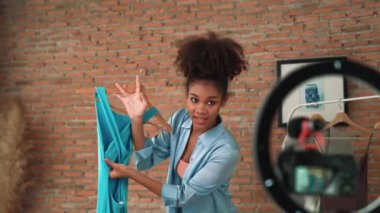 Kadın nüfuzlu kişi canlı yayında video görüntülerini çekiyor. Kıyafetler sosyal medya ya da blog için çok önemli. Stüdyo ışıklandırmalı mutlu genç kız çevrimiçi pazarlama oturumu yayını için..