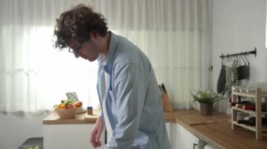 Mutlu baba yemek pişirirken müziğe geçiyor ve modern mutfakta öğle yemeği hazırlıyor. Aktif baba, sebze ve mutfak gereçleri ile çevrili sağlıklı yemek ya da salata yaparken şarkıyla dans ediyor. Pedagoji.