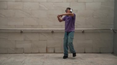 Yakışıklı hippi dans ederken müzik dinler ya da dans ederken dans eder. Çekici bir sokak dansçısı B-boy ayak sesleri çıkarıyor. Serbest dans konsepti. Yaşam tarzı. Açık hava sporu 2024. Yumuşak bir şekilde..