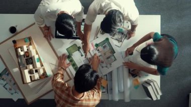 Mimar mühendis ekibinin tartıştığı ve tablet görüntüleme inşaatını planlı ve ev modeliyle toplantı masasında işaret ettiği en tepeden aşağı bakış açısı. Çeşitli tasarımcı tasarım evleri. Hizalama.