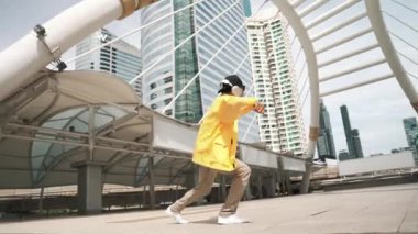 Asyalı şık bir adam alçak açılı kamerayla hip hop dansı yapıyor. Break dansçı, şehirde kulaklıktan müzik dinleyip dans ederken merdivenlerden çıkıyor. Açık hava sporu 2024. Yumuşak bir şekilde..