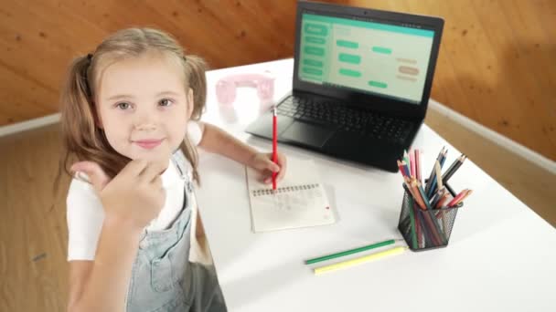 親指のジェスチャーを見せながら 授業をしている かなり慎重な女の子 Stemテクノロジークラスでエンジニアリングプログラミングコードを見ながら ノートブックで子供のライティングプラン エラー — ストック動画