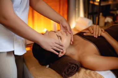 Beyaz kadın stres önleyici kafa masajı yapmaktan ve lüks otel veya otelde sıcak mum ışığında yüz güzelliği eğlencesi yapmaktan zevk alıyor. Sessiz.