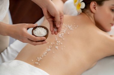 Lüks spa salonlarında sıcak mum ışığında cilt bakımı yaptıran kadın müşteri. Sağlık Spa vücut fırçasında tuz temizleme güzellik tedavisi. Sessiz.