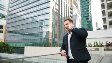 Yetenekli bir iş adamı pazarlama ekibiyle pazarlama stratejisi hakkında konuşurken gökdelende dururken telefon kullanıyor. Mutlu yönetici, modern kentsel şehirdeki satışları arttırmak için meslektaşını arıyor. Urbane.