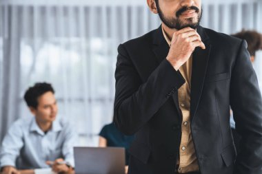 İş adamı, toplantı odasının arka planında çeşitli iş arkadaşlarıyla güven içinde poz veriyor. Çok kültürlü ekip iş başarısı için birlikte çalışır. Modern iş adamı portresi. Uyum