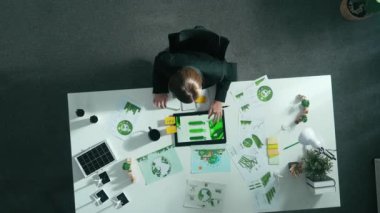 Akıllı yöneticilerin yeşil iş yatırımları hakkında karar vermeleri. Yeşil enerji ve sıfır atık hakkındaki belgelerle toplantı masasında çalışan yetenekli bir iş kadınının havadan görünüşü. Hizalama.