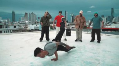 İspanyol hipster dansları şehrin mavi gökyüzü manzaralı çok kültürlü arkadaşlarıyla çevrili. Çatıda bir grup sokak dansçısı sahne alıyor. Aktif, eğlenceli, mutlu atmosfer. Açık hava sporu 2024 hiphop..