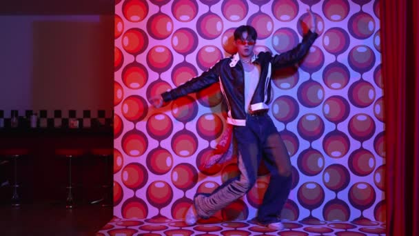 アジアのブレイクダンサーがフリースタイルの音楽に移動し 気球の背景を持つステージでカメラを見ています カジュアルな衣装と豪華な眼鏡を身に着けているプロのヒップスター レギュレーション — ストック動画