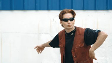 Beyaz arka planda break dans pratiği yapan yakışıklı bir sokak dansçısı. Hip hop tarzı giyinen sporcu, mavi arka planlı bir sokakta müzik eşliğinde ayak sesleri çıkarıyor. Açık hava sporu 2024. ÇalışmaComment.