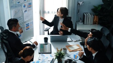 Akıllı yönetici projesinin üst görünümü beyaz tahtaya zihin haritası ve finansal grafik ile işaret ediyor ve çeşitli yatırımcılar hisse yatırım grafiğini dinleyip analiz ederken pazarlama fikrini açıklıyor. Müdürlük.