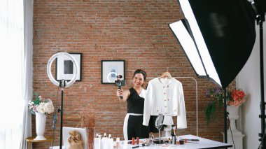 Kadın nüfuzlu kişi video görüntülerini canlı yayınlıyor. Sosyal medya ya da blog. Stüdyo ışıklandırması olan mutlu genç bir kız pazarlama için internet üzerinden yayın yapıyor..