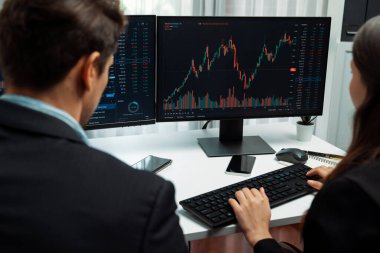 Dinamik borsada döviz kuru yatırımını tartışan iki ticaret simsarı iki bilgisayar ekranında gerçek zamanlı risk grafiği ya da modern ofisteki kar noktasını karşılaştırıyor. Varsayım.