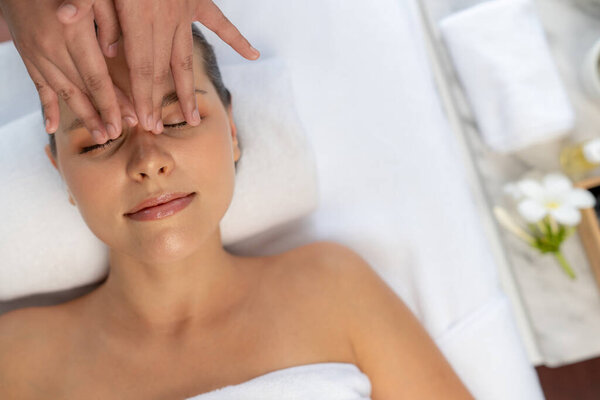 Panorama top view of woman enjoying relaxing anti-stress head massage and pampering facial beauty skin recreation leisure in dayspa modern light ambient at luxury resort or hotel spa salon. Quiescent