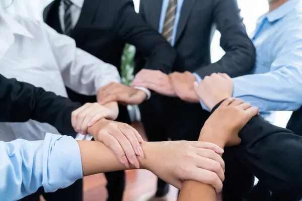 多文化ビジネスの人々が輪になって手を携えている オフィスビジネスの職場での団結チームワーク チームビルディングに従事する多様な民族のオフィスワーカー 細心の注意を払って ロイヤリティフリーのストック画像