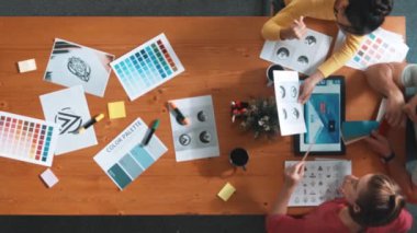 Proje yöneticisi renk paletleri seçerken tasarımcının tablete baktığı yukarıdan aşağıya hava görüntüsü. Profesyonel grafik tasarımının en üst görüntüsü ve logoya bakın. Yetenekli ekip grafikleri seçiyor. Sempozyum.