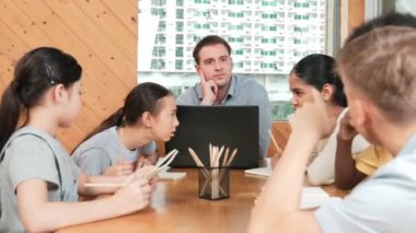 Akıllı öğrenci çalışmalarını kontrol ettiği için mutlu öğretmen diye el kaldırdı. Liseli kız not defterine bakan yetenekli bir öğretmen ve sınıfta onu cesaretlendiren bir başparmak gösteriyor. Yaratıcı. Öğretim