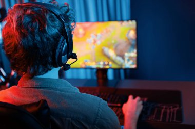Savaş arenasında çoklu oyunlar takımıyla Moba 'da savaşan genç oyun flamasının sunucu kanalı, neon dijital ışık modern odasındaki arka görüntü ile bilgisayar monitöründe kulaklık takıyor. Toplayıcı.
