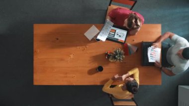 Proje yöneticisinin yürüme ve katılma görüşünün üst görüntüsü dizüstü bilgisayar kullanarak ve renk paletleriyle toplantı masasında otururken. İş adamlarının hava görüşü renkler hakkında konuşuyor. Sempozyum.