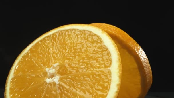 オレンジ色のスライスのマクログラフィーのキャプチャーは 洗練された孤立した黒い背景に置かれ 柑橘類の視覚的な傑作として展開されます 黒い背景を持つオレンジ色のスライス プリスティブル — ストック動画