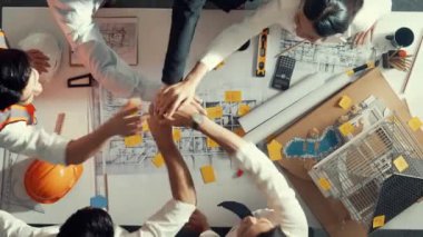 Akıllı inşaat mühendisinin ev modeliyle toplantı masasında el ele tutuşması. Toplantı odasında el ele tutuşurken mimar takımının birlikte çalışmasını gösteren hava görüntüsü. Hizalama.