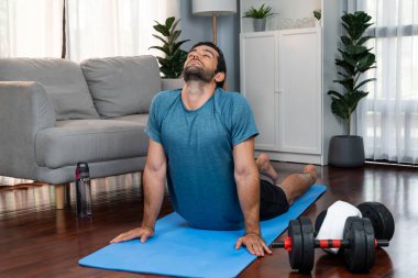 Atletik ve sporcu adam, evdeki fiziğe ve sağlıklı spor yaşam tarzına uygun vücut egzersizlerinden önce ısınıyor ve esniyor. Gaiety ev egzersizi antrenman konsepti.