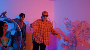 Stüdyoda gündelik kıyafetleri olan çok kültürlü bir arkadaş tezahürat yaparken mutlu hipster break dansları. Profesyonel sokak dansçısı hip hop ritmi ya da neon veya kurşun ışıkla kafiyeli bir şarkı söyler. Mutluluk.