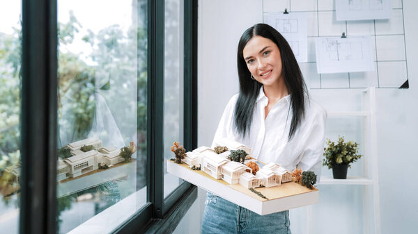 Крупный план квалифицированного молодого красивого кавказского архитектора лифта дом модели левой и правой стороны, чтобы проверить и сосредоточиться на проверке ошибок точки в современном офисе с чертежом. Непорочный.