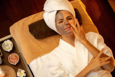 Kaplıca salonunun sakin atmosferi, üst düzey kadın müşteri sıcak mum ışığında kömür kömürü yüz kremi masajıyla kendini yenilemeye çalışıyor. Yüz bakımı ve güzellik konsepti. Sessiz.