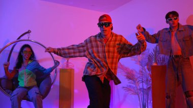 Stüdyoda gündelik kıyafetleri olan çok kültürlü bir arkadaş tezahürat yaparken mutlu hipster break dansları. Profesyonel sokak dansçısı hip hop ritmi ya da neon veya kurşun ışıkla kafiyeli bir şarkı söyler. Mutluluk.