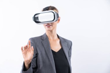 Profesyonel kadın lider programa dokunuyor ya da sanal gerçeklik gözlüğü kullanırken çalışıyor. Yetenekli iş kadını, görsel gerçeklik gözlüğü takarak metaevrene bağlanırken sistemi işaret ediyor. Kısıtlanma.