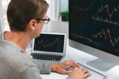 Bilgisayar ve dizüstü bilgisayarı kullanarak, çalışma masasındaki dinamik artırılmış borsa grafiğinin en yüksek kar değerini araştıran bir tüccar, modern ofisteki ekrandaki döviz kuru değerini analiz ediyor. Bireysel.