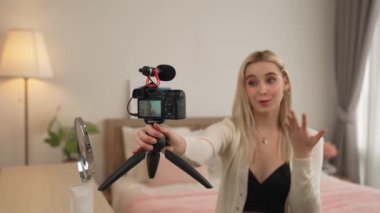 Sosyal medya için güzellik ve kozmetik video içeriği hazırlayan genç bir kadın. Seyirciye veya takipçiye nasıl sıvı ruj sürüleceğini gösterirken kamera ve ışık halkası kullanan bir güzellik blogcusu. Blithe